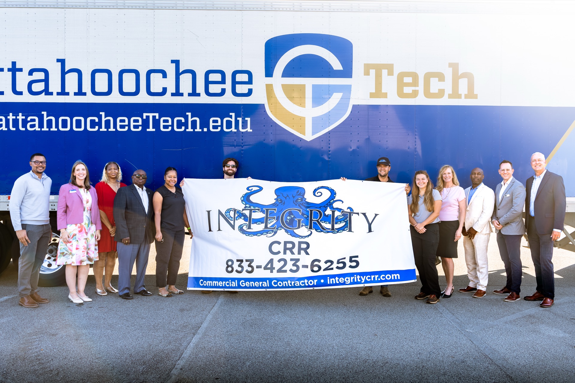 The Integrity CRR team and fellow attendees holding the company banner at Chattahoochee Tech.