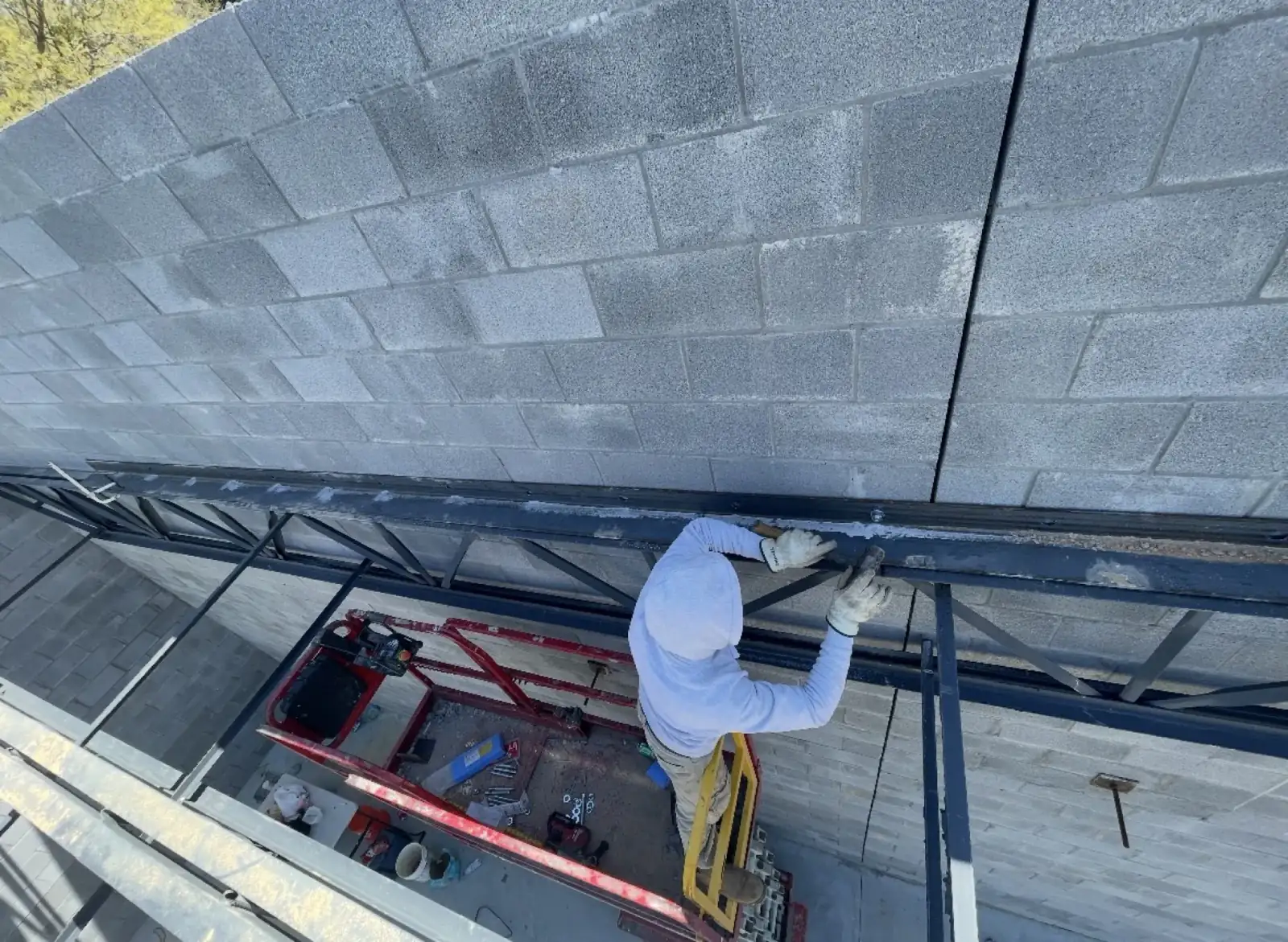 Worker fastening steel framing beside a CMU wall on a Georgia commercial construction site