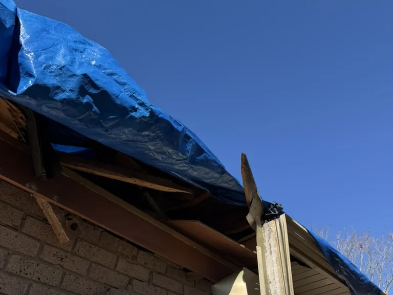 Broken rafters and fascia under an emergency tarp