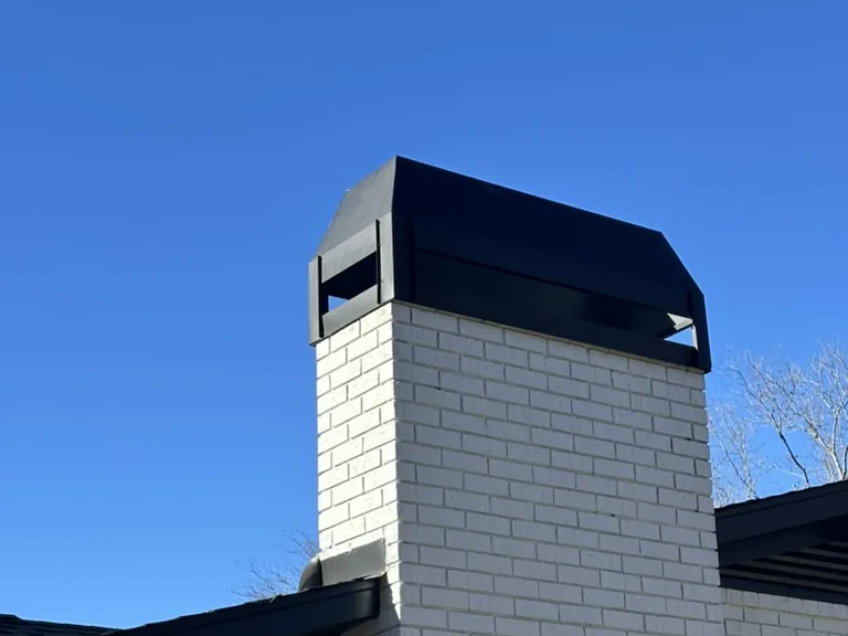 Painted brick chimney finished with a black metal chimney cap