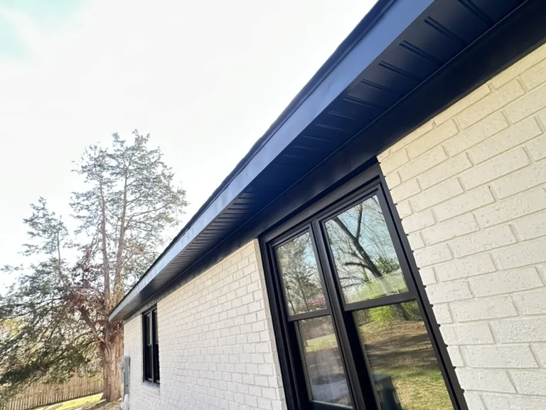 Finished exterior with black fascia, soffit, and windows on painted brick